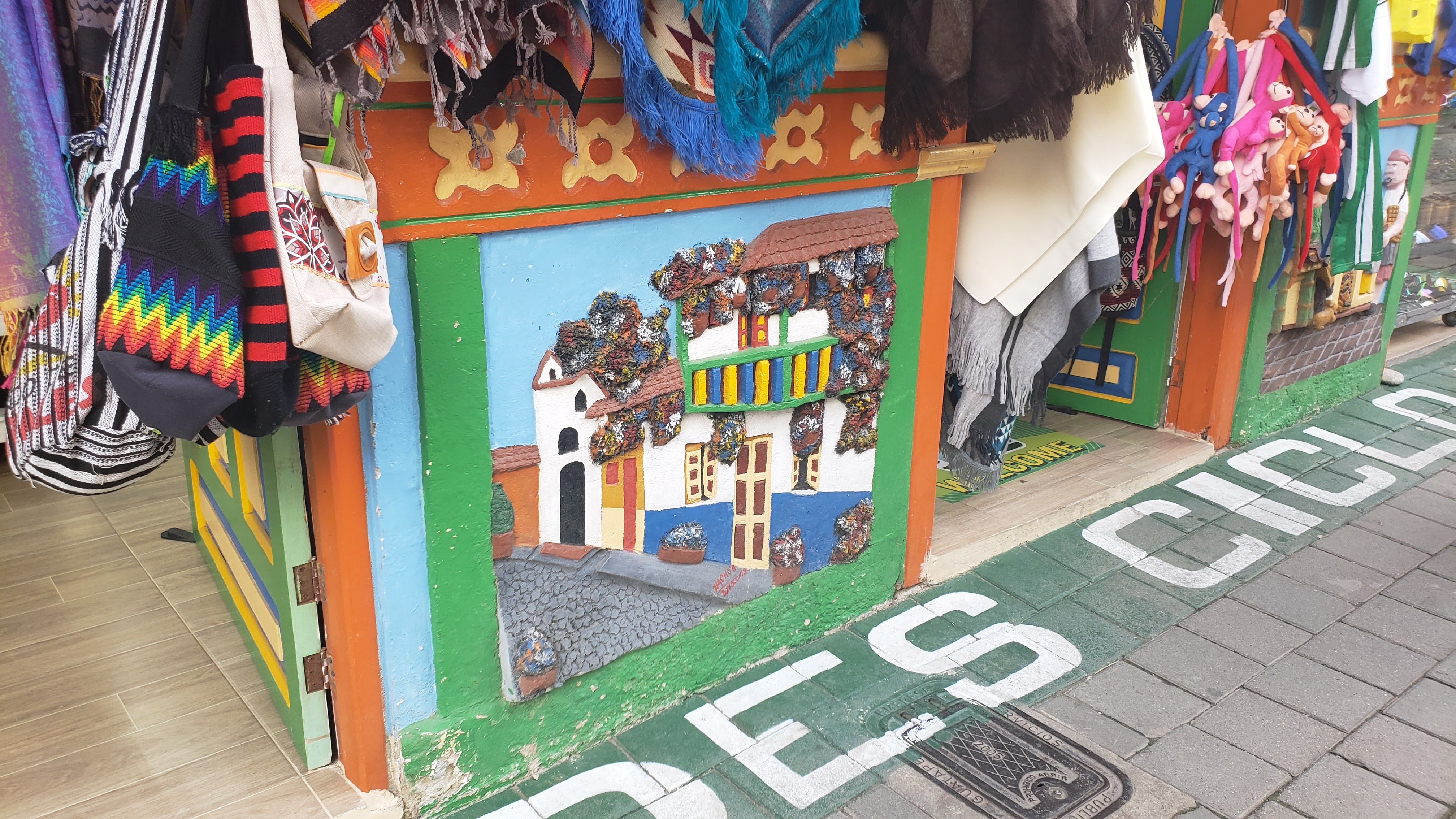 Bas relief of a colorful home with lots of flowers on a cobblestone street