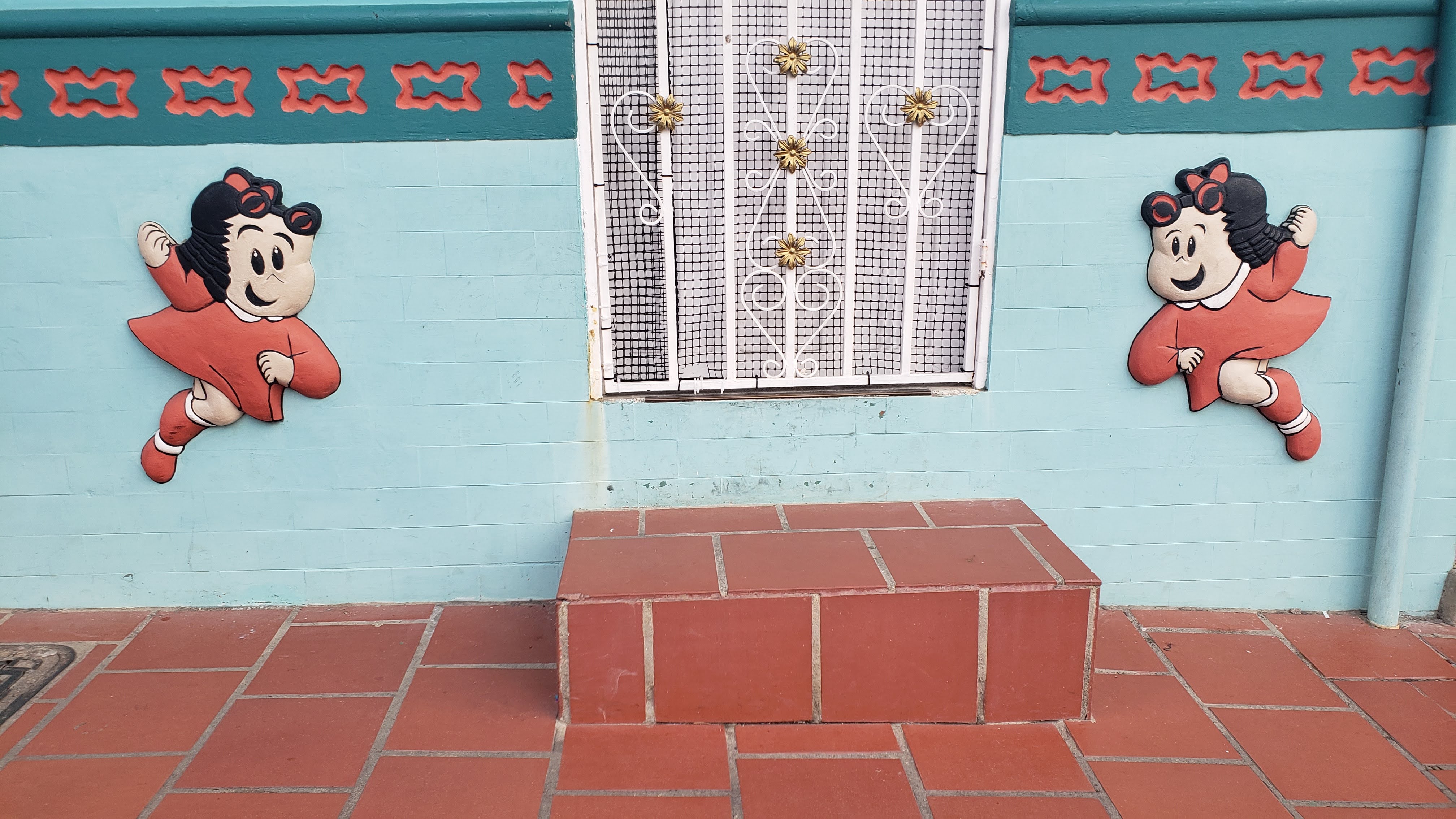 Bas relief of a comic strip style girl in a red dress on either side of a door on a light blue background