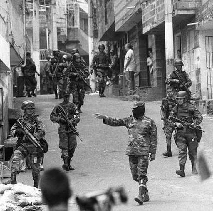 Soldiers walk the narrow streets of Comuna 13, led by a black-masked officer