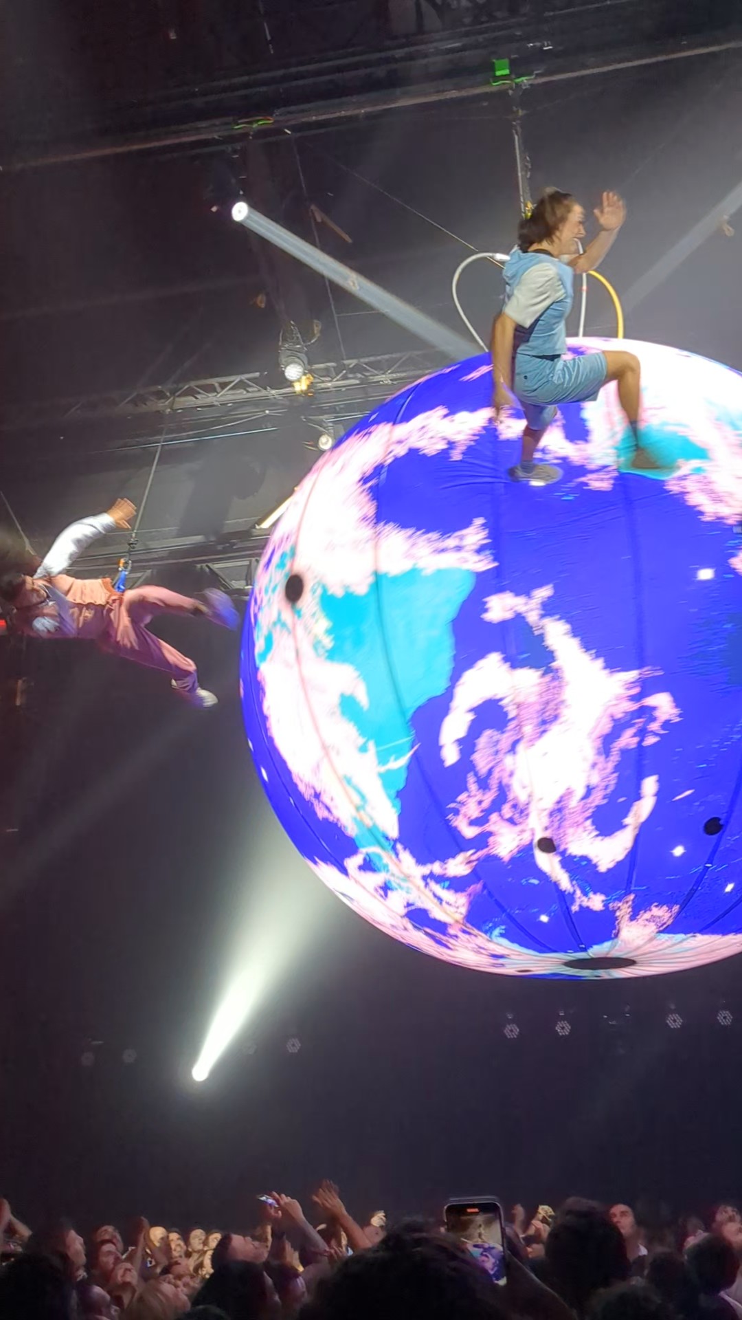 Large, inflated globe suspended above the crowd with performers also suspended and "running" on the equator of the globe
